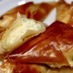 Greckie pierogi pierogi z serem przygotowane z ciasta filo wypełnionego serem lub mieszanką serów, pokrojonego na kawałki, złożonego w trójkąty i upieczonego.