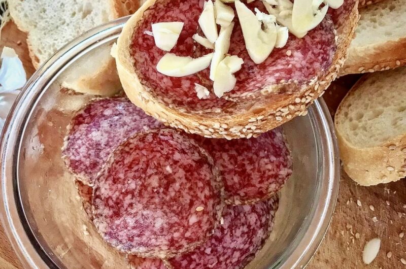 kromka białego pieczywa z plasterkami węgierskiego salami oraz z siekanym drobno czosnkiem