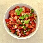 Salsa pomidorowa przygotowana z drobno pokrojonych dojrzałych pomidorów, papryczki jalapeno, czerwonej cebuli, dymki i świeżej kolendry skropionych obficie sokiem z limonki.