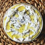 Turecki sos cacik przygotowany z gęstego jogurtu z dodatkiem startych ogórków, dymki, czosnku i soku z cytryny.