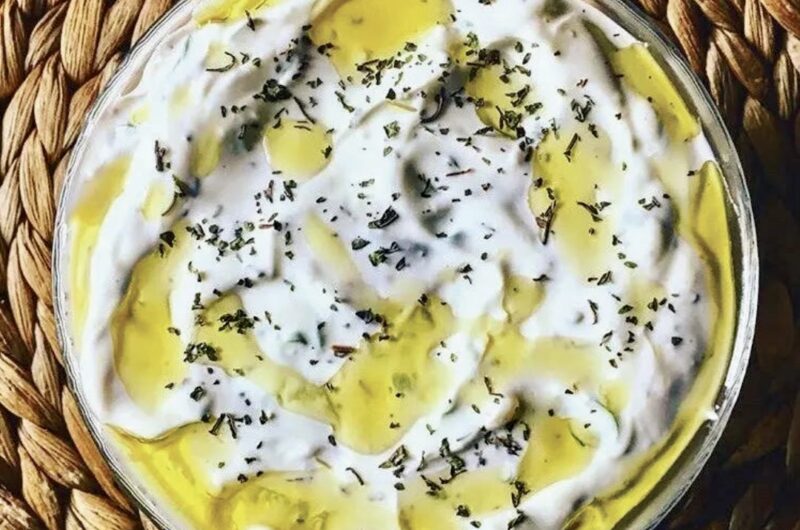 Turecki sos cacik przygotowany z gęstego jogurtu z dodatkiem startych ogórków, dymki, czosnku i soku z cytryny.