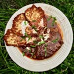 Karkówka wieprzowa pocięta na kotlety i duszona w sosie paprykowym, a następnie podane z chrupiącymi plackami ziemniaczanymi w sosie powstałym podczas duszenia mięsa.