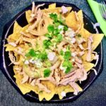 Chilaquiles z czipsów kukurydzianych polanych sosem przygotowanym z dodatkiem ostrych papryczek i pomidorów. To popularne danie na meksykańskie śniadanie podaje się z gotowanym poszarpanym mięsem z kurczaka.