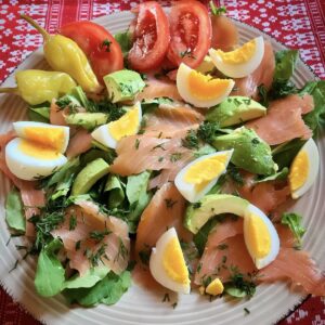 sałatka z awokado, łososiem wędzonym, jajkiem i pomidorami na talerzu