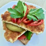 Schabowy z kurczaka to kotlet wycięty z piersi kurczaka panierowany i smażony jak tradycyjny kotlet schabowy, podany jednak na kromce chleba razem z krojonym domowym ogórkiem kiszonym.