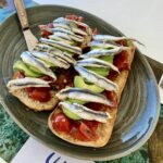 Bruschetta z awokado czyli włoska kanapka przygotowana na świeżej bułce obłożona salsą pomidorową z oliwą i bazylią, a następnie wzbogacona o awokado i rybki marynowane.