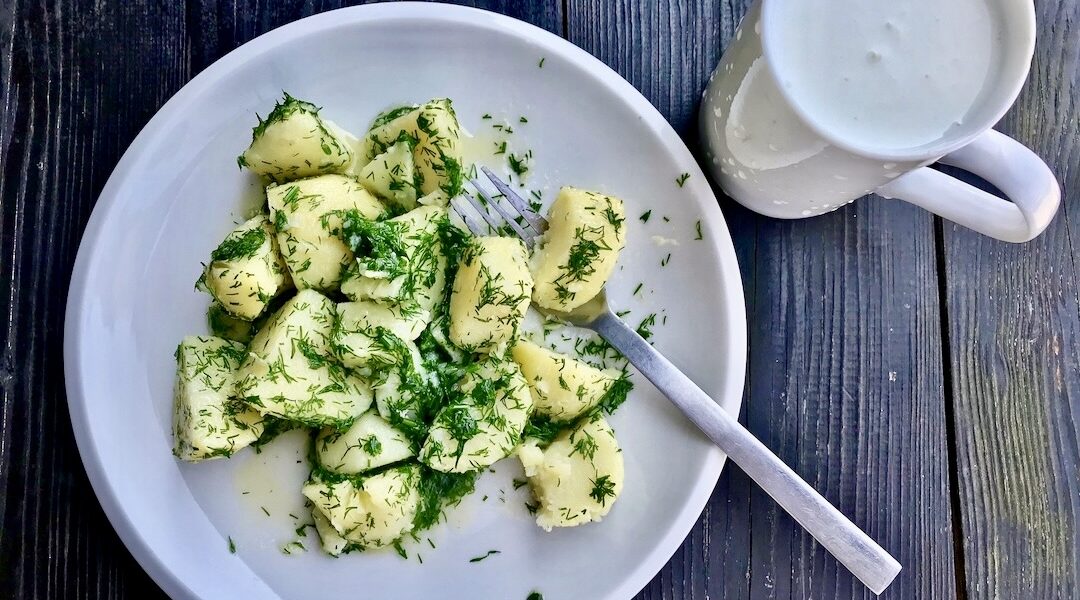 Młode ziemniaki gotowane, a następnie odcedzone i połączone z masłem i siekanym koperkiem serwowane z zimnym kefirem.