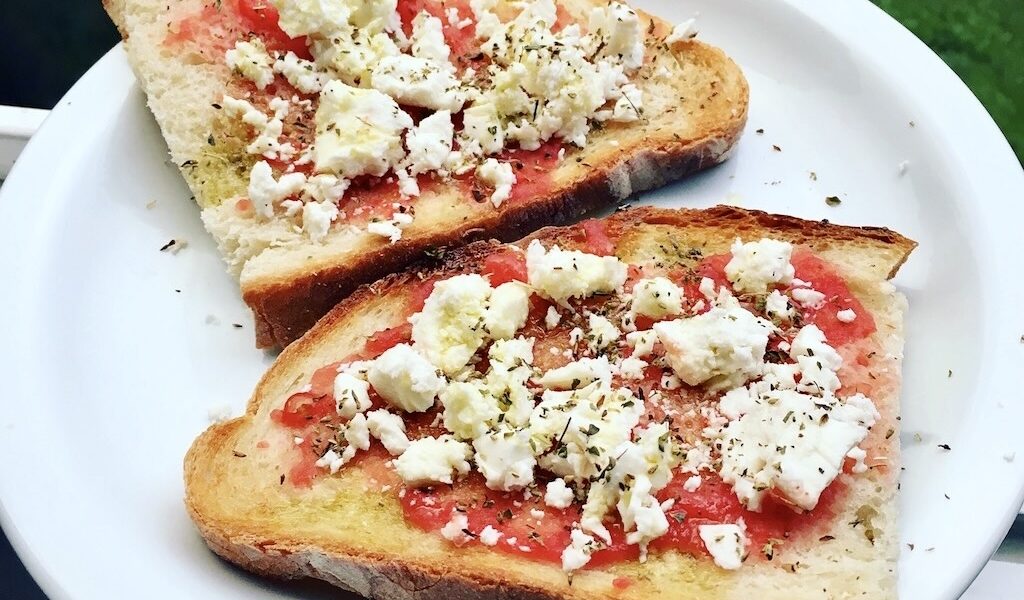 Grzanki z pomidorem powstały z kromek chleba skropionych oliwą, obsmażonych na chrupiąco, a następnie z startym pomidorem i słoną fetą prosto z Grecji.