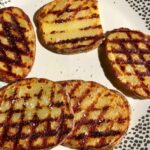 Ziemniaki z grilla przyrządzone z talarków wykrojonych z ziemniaków, grillowanych na ruszcie i podanych z masłem czosnkowym, solą morską i suszonym oregano.