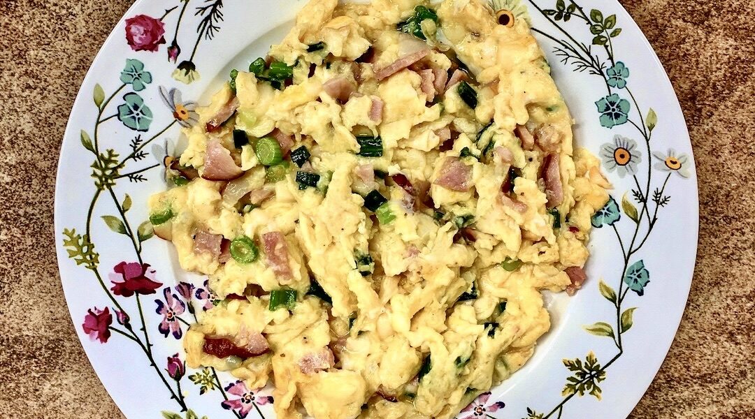 Jajecznica na boczku, czyli jajka rozkłócone i smażone razem z pokrojonym w drobną kostkę boczkiem surowym wędzonym wzbogacona smakiem dymki.