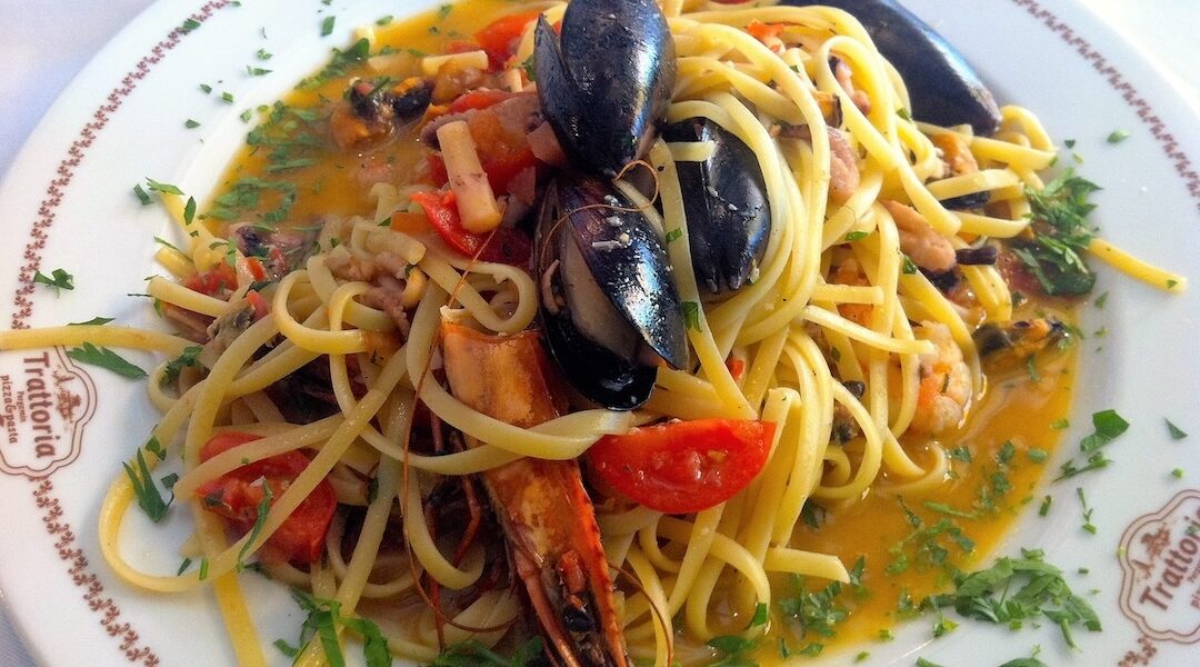 Makaron ugotowany al dente podany na dużym talerzu w sosie z oliwą i owocami morza.