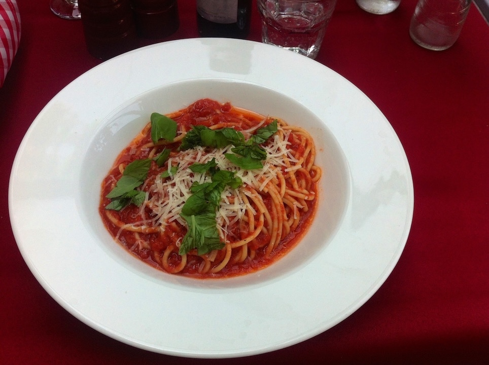 W głębokim talerzu znajduje się makaron spaghetti zalany zbyt dużą ilością sosu pomidorowego