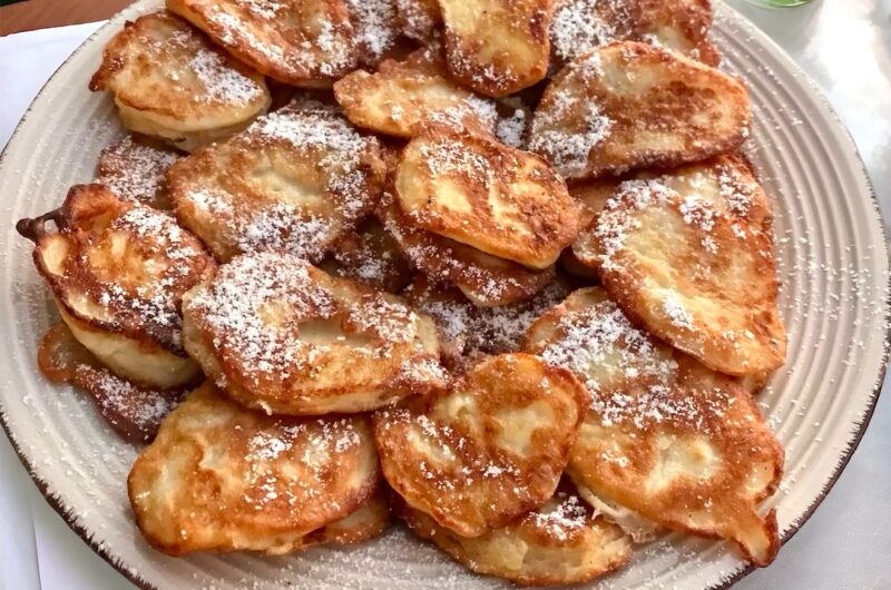 Racuchy z jabłkami, czyli małe placki przygotowane z plasterków jabłek otoczonych ciastem naleśnikowym, usmażone na złoto, posypane cukrem pudrem.