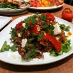 Sałatka z soczewicy i fety z dodatkiem czerwonej papryki i suszonych pomidorów na dużym talerzu