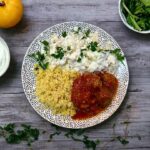 Surówka z kapusty pekińskiej z sosem czosnkowym podana na talerzu z pulpetami w sosie pomidorowym oraz z kuskusem