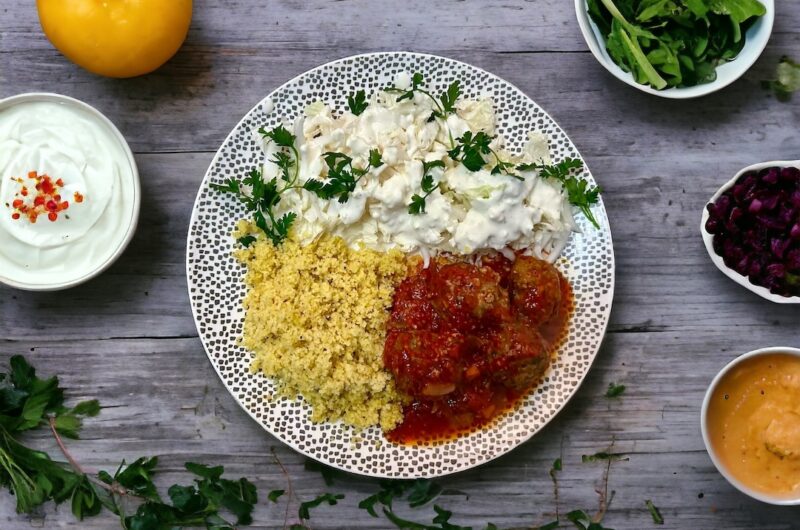 Surówka z kapusty pekińskiej z sosem czosnkowym podana na talerzu z pulpetami w sosie pomidorowym oraz z kuskusem