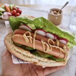 Domowy hot dog z parówkami sałatą ogórkiem i rzodkiewką