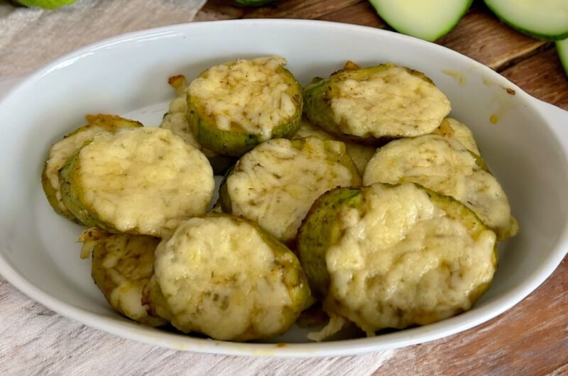 cukinia pokrojona w plastry, obłożona startym serem i czosnkiem, a następnie krótko zapiekana