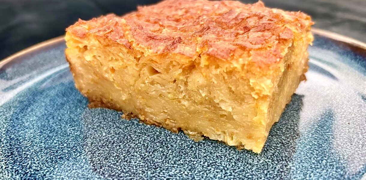 portokalopita greckie ciasto pomarańczowe przyrządzane z ciasta filo z dodatkiem pomarańczy i soku pomarańczowego na niebieskim talerzu