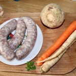 trzy laski surowej białej kiełbasy leżą na talerzu
