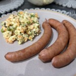 sałatka jarzynowa na talerzu podana z dwoma frankfurterkami