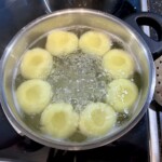 kluski śląskie górują się w dużym garnku we wrzącej wodzie