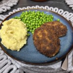kotlet pożarski na talerzu podany z ziemniakami puree oraz groszkiem z masłem