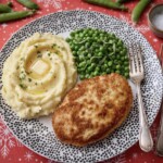 kotlet pożarski na talerzu razem z ziemniakami puree oraz groszkiem zielonym z masłem