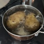 w garnku gotują się dwa duże ziemniaki