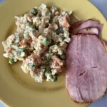 sałatka jarzynowa na talerzu z plasterkiem szynki gotowanej