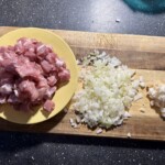 pokrojone w kostkę mięso oraz siekana cebula na desce kuchennej
