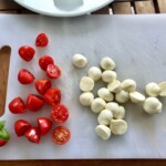 pomidorki koktajlowe przekrojone na połowę, tak samo mozzarella kulki