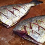 dwie ryby dorada bez głów leżą na blacie kuchennym