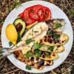 dorada z grilla po chorwacku podana z pieczonymi plastrami ziemniaków oraz pomidorami