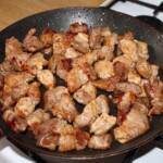 na dużej patelni smaży się wieprzowina pokrojona w kostkę