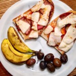 grzanki z szynką i serem z Krety podane na talerzu z oliwkami i lokalnymi bananami