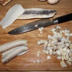 na desce kuchennej krojony jest filet śledziowy