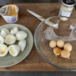 w szklanym naczyniu znajdują się żółtka ugotowanych jajek, obok miski znajdują się białka jajek ugotowanych