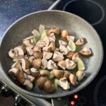 na patelni smażą się pieczarki pokrojone w ćwiartki