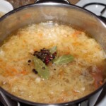 w dużym garnku gotuje się żeberko wędzone, kapusta kiszona z przyprawami na kapuśniak