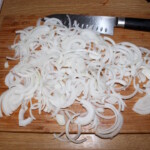 pokrojona w piórka cebula na desce kuchennej