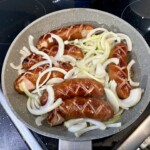 na patelni smażą się laseczki kiełbasy śląskiej razem z celu pokrojoną w piórka