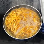 w garnku gotują się w wodzie siekane skórki z pomarańczy
