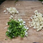 na blacie kuchennym leżą posiekane drobno czosnek i dymka