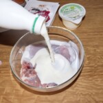 udka z królika znajdują się w szklanej misce i są zalewane kefirem do smaku