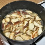 w garnku gotują się pokrojone świeże grzyby