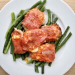 medaliony wieprzowe z salami i serem halloumi podane na talerzu z gotowaną zieloną fasolką szparagową