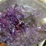 w garnku gotuje się posiekana czerwona kapusta