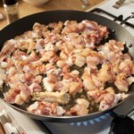 na wielkiej patelni smażą się małe kawałki mięsa