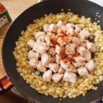 na dużej patelni smaży się drobno siekana cebula oraz pokrojony w małą kostkę filet z kurczaka
